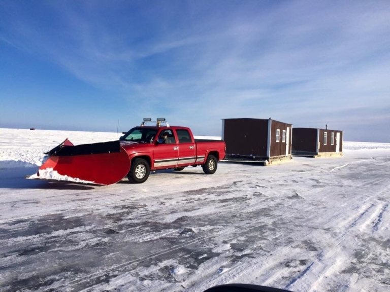 Truck with a snowplow blade and ice cabins.