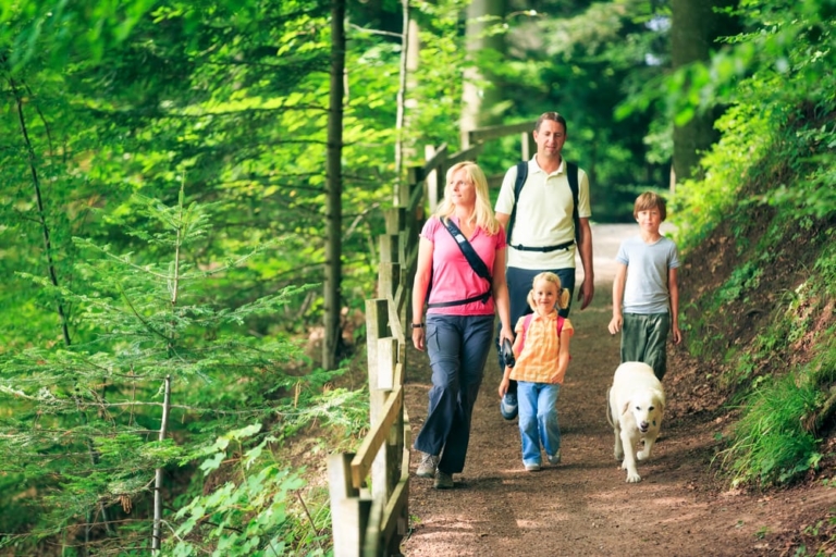 Family with a dog walking along a trail.