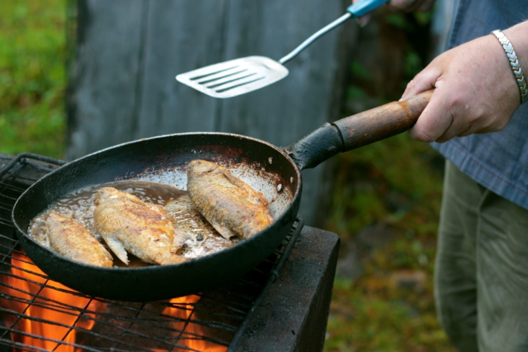 Person pan frying fish.