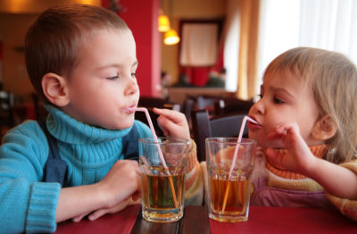 two kids sipping on a drink