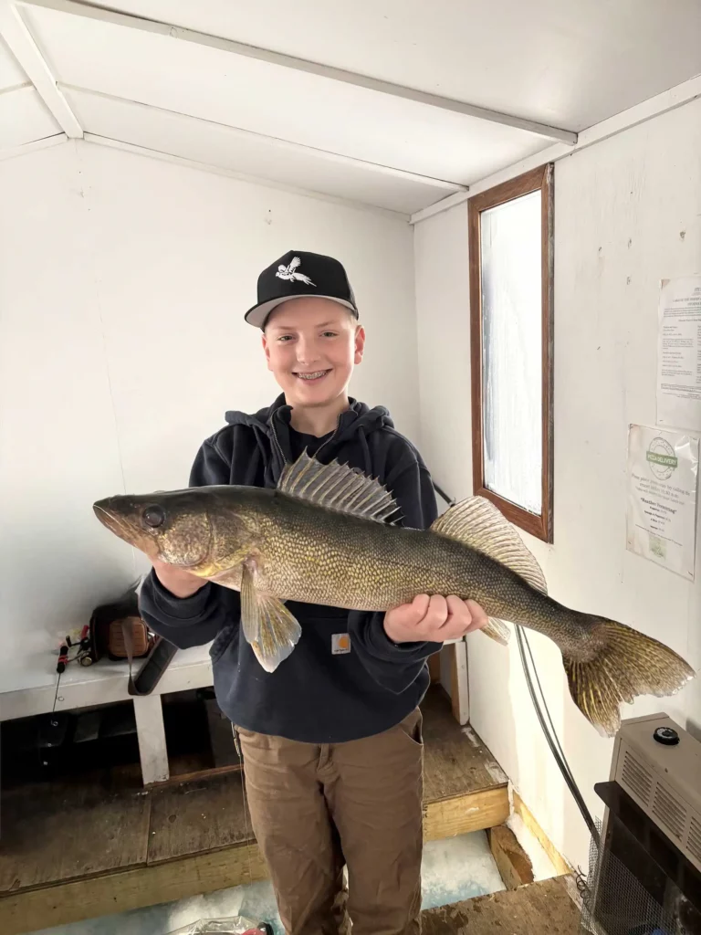 trophy walleye lake of the woods fishing report Boy in a cap holding a large walleye indoors.