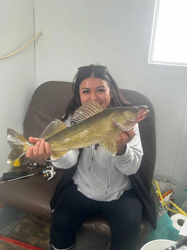 walleye catch ice fishing river bend resort Woman seated in an ice house holding a walleye.